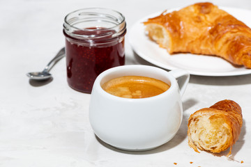 cup of espresso and fresh croissants, berry jam on white table