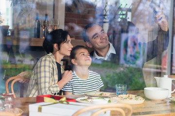 Fototapeta na wymiar A happy family taking a selfie inside the cafe