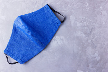Face protective mask. Antivirus mask made from denim. Blue white denim face mask during a pandemic virus COVID-19. Protective mask on a gray background