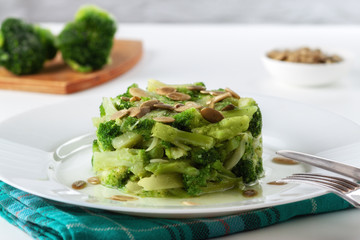Boiled broccoli with pumpkin seeds on a white plate on the table