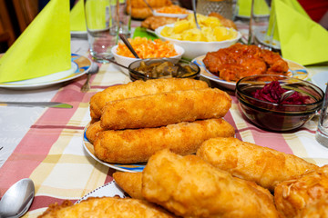 A pile of fried, stuffed Polish croquettes lying on a decorated table, visible mushrooms and beets.
