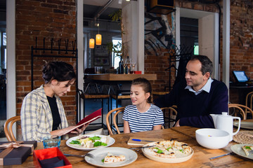 A family reading a book after a nice meal