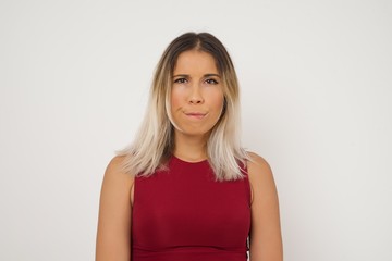 Obraz premium Pensive attractive blonde female being deep in thoughts, raises eyebrows, curves lips, wears fashionable clothes, stands against gray wall with copy space for your text.