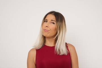 Troublesome puzzled Caucasian woman frowns face, bites lip, raises eyebrows, looks up, has problems, dressed in fashionable clothes, isolated over gray background, has regret look.