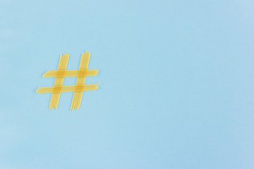 Hashtag sign made of spaghetti on a blue background. Social Media Concept.