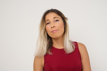 Close up studio shot of beautiful young mixed race woman model with curly dark hair looking at camera with charming cute smile while posing against white blank copy space wall for your content