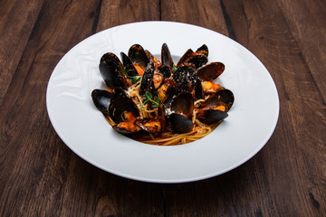 Seafood pasta spaghetti with mussels and tomatoes served on a wooden table