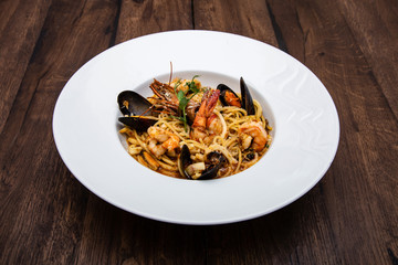 Seafood pasta spaghetti with mussels and Royal shrimp served on a wooden table. 