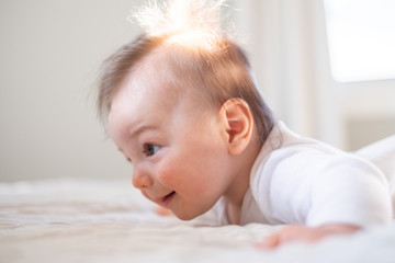 Portrait of a baby boy in the bedroom with bright light