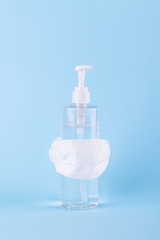 Gel hand sanitizer is wearing a white surgical mask on a blue pastel background. self igiene concept, protect yourself for coronavirus