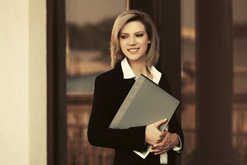 Happy young business woman with a file folder at office building