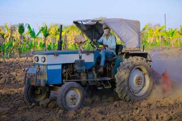 Obraz premium Indian / Asian farmer with tractor preparing land for sowing with cultivator, An Indian farming scene