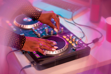 Fototapeta na wymiar Hands of African female deejay moving turntable and mixing sounds
