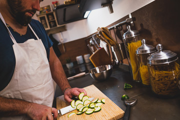 young man cut zucchini at the home during the lockdown for covid 19