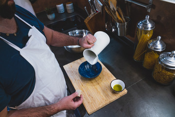 boy prepares a pizza dough following a recipe on the tablet in his home kitchen during the lockdown for covid 19