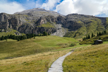 Fototapeta na wymiar Beautiful day for a hiking trip to distinctive Sassopiatto, Langkofel in South Tyrol. Path leads to the distinctive mountain. Travel, Adventure and holiday concept.