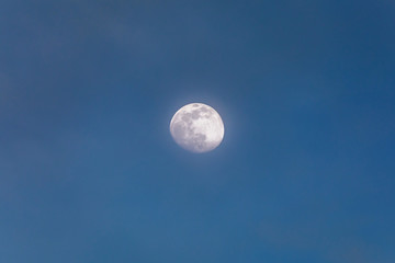 Crescent moon on daytime sky. The moon in the daytime on a blue sky with a light haze. Crescent moon to 3/4 of visible surface.