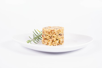 Risotto with button mushroom and bacon decorated with rosemary twig on a plate on a white background