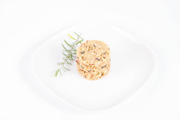 Risotto with button mushroom and bacon decorated with rosemary twig on a plate on a white background