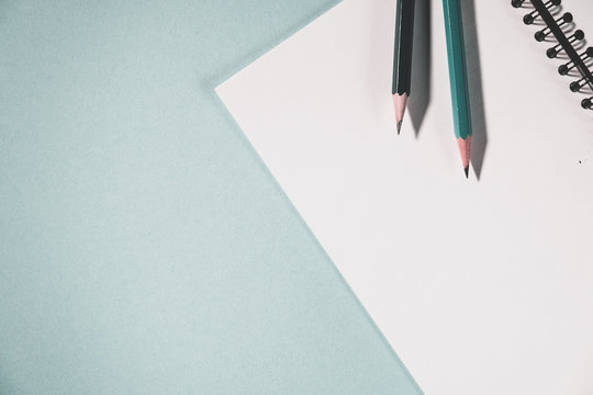 pencils and spiral notebook on a pastel light background. Notebook with blank clear page on the table.