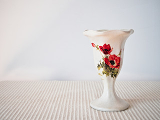white vase decorated with floral motif of poppies on light background