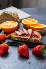 Healthy fruity breakfast, bread with jam and slice of orange and strawberry.