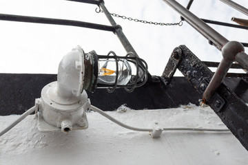 Vintage caged metal light fixture on the exterior of an old ship vessel, heavy paint, horizontal aspect