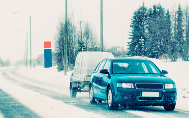 Car with trailer in road in Rovaniemi winter Lapland Finland reflex