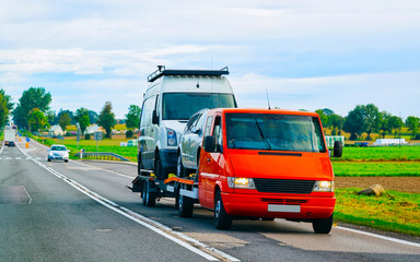 Fototapeta na wymiar Car carrying trailer with mini vans on road of Slovenia reflex