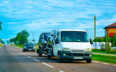 Fototapeta na wymiar Car carrying trailer with new vehicles at road in Slovenia reflex