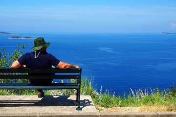 Naklejka na ściany i meble Man relaxing on a bench on the seaside