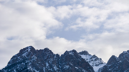 close-up view of the mountain peak with trees and snow on it cloudy day.