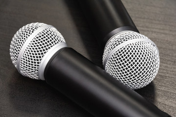 Obraz premium Top view: two microphones lie on a wooden table. Preparation before speaking at the conference