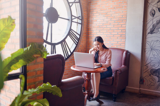 Asian  woman while using her tablet.asian businesswoman wearing black business suit uniform, using tablet with smiling and confident face on white background.home working