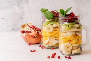 Colorful fruit salad in a mason jar on rustic concrete background front view