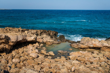 Fototapeta na wymiar rocky coast and blue sea with waves