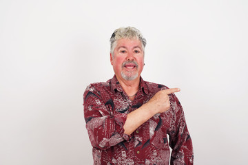 Look over there! Handsome blond caucasian man pointing away and smiling to you while standing against grey background.