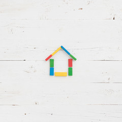 Directly above on colorful wooden toy blocks in the shape of a house on a white background wooden table.
