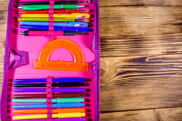 Different school stationeries (pens, pencils, felt tip pens and protractor) in a pink pencil box....