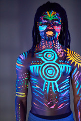 black african man with fluorescent bodyart, ethnic prints of shirtless muscular body. studio shot