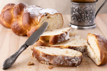 Sliced fresh bread and a vintage knife. Tea in a glass cup with a cup holder nearby. Crumbs of bread. Light wooden background. Side view. Closeup
