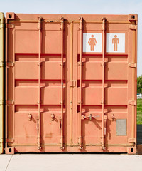 White screen printing of a public toilet symbol on an orange shipping container