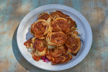 Top view on vintage porcelain plate with homemade italian style pizza scrolls made from puff pastry and filled with mozzarella cheese and  fresh tomato sauce with herbs like oregano. Snack for vine.