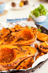 Close up baked roasted grilled whole orange pumpkin butternut squash halfs and sweet potato slides with herbs on baking sheet on blue napkin. Vegetarian and vegan food diet. Healthy eating. Vertical