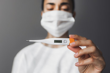 Patient in medical mask holding thermometer with high temperature. Covid-19 and Flu Virus Symptom....