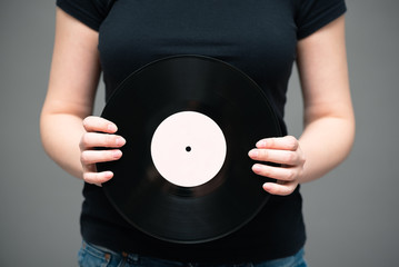 A vinyl record in singer hand on gray background.