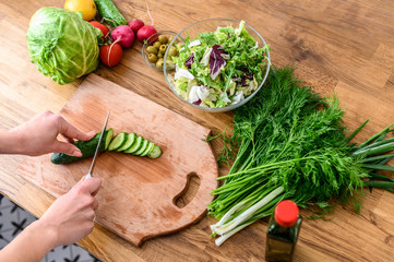 Hands of woman are slicing cucumber