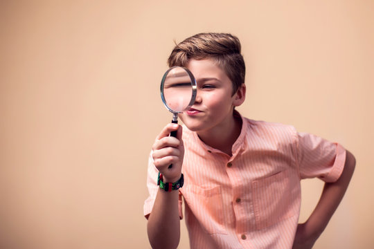 A portrait of kid boy holding magnifier. Children and knowlage concept