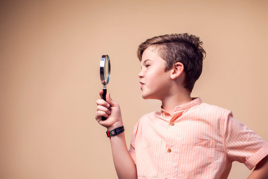 A portrait of kid boy holding magnifier. Children and knowlage concept