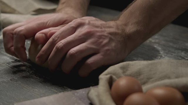 Baker hands kneading dough in flour on wooden table. Bakery concept. Close-up of manufacturing process in 4K, UHD